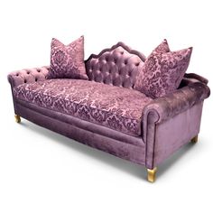 a purple couch with two pillows on it and some gold trim around the armrests