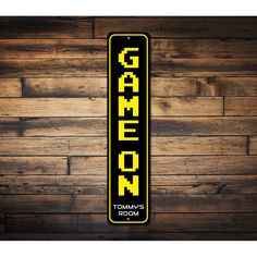 a yellow and black sign that says game room on the side of a wooden wall