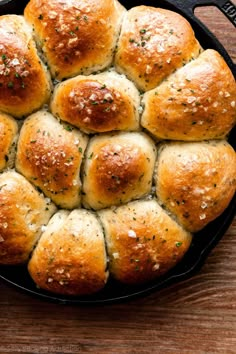 a skillet filled with bread rolls covered in cheese and parmesan sprinkles