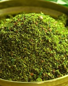 a metal bowl filled with green moss on top of a table