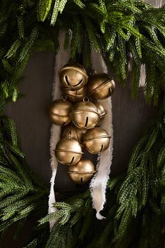 a bunch of bells hanging from the side of a christmas tree with pine needles on it