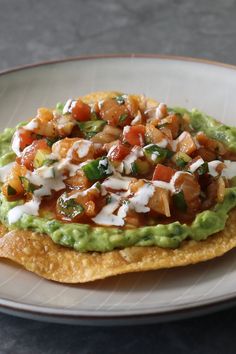 a tortilla topped with guacamole, tomatoes and other toppings