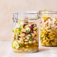 two glass jars filled with food sitting on top of a table next to each other