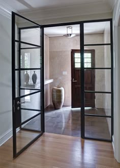 an open door leading to a bathroom with a vase on the wall and wooden floors