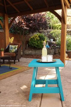 a blue picnic table with a bottle of wine on it in the middle of a patio