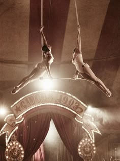 two circus performers hanging upside down on ropes