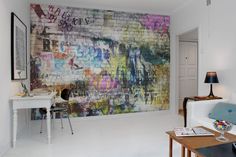 a living room filled with furniture next to a wall covered in grafitti art