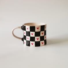 a black and white checkered coffee cup with hearts on it