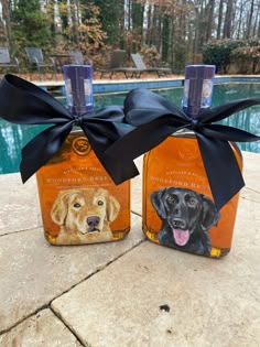 two bottles with dogs on them are sitting next to a swimming pool and one has a black bow