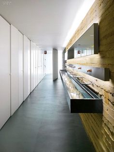 a long hallway with white cabinets and mirrors on the wall, leading to another room