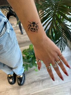 a lady bug tattoo on the left wrist