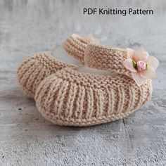 a pair of knitted baby shoes sitting on top of a cement floor next to a wall