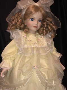 a doll with blonde hair wearing a yellow dress and veil on it's head