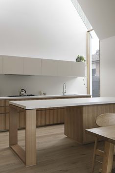 a kitchen with wooden floors and white counter tops next to an open window on the wall