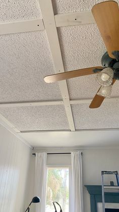 a ceiling fan is hanging from the ceiling in a room with white walls and windows