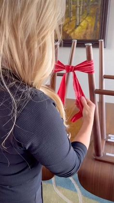 a woman is holding up some red ribbon to tie it around the chair legrests