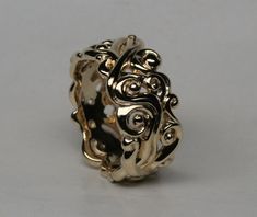 an intricately designed ring is shown on a white surface, with the center piece in gold plated metal