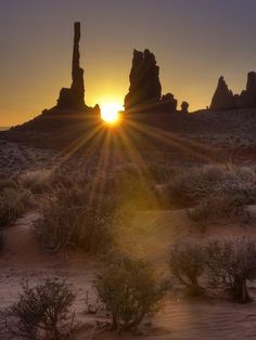 the sun is setting behind some rocks in the desert