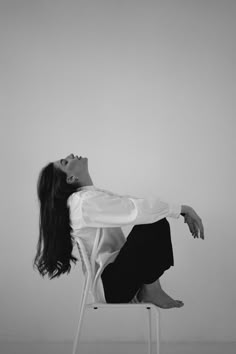 a woman sitting on top of a white chair