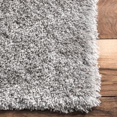 a close up view of a gray rug on a wooden floor with wood planks in the background