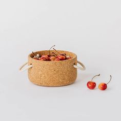 two cherries sitting in a cork container next to each other on a white surface