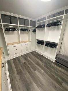 an image of a walk in closet with white cabinets and gray drawers on the bottom shelf