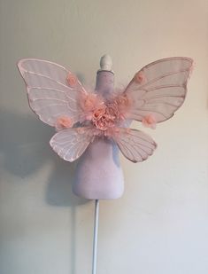 a mannequin headdress with pink flowers and wings