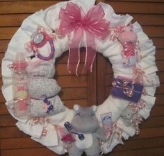 a wreath made out of diapers and stuffed animals on the front door with pink bows