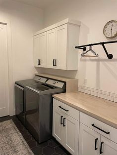 a washer and dryer in a room with white cupboards on the wall