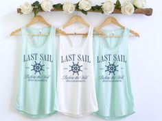 three women's tank tops hanging on a rack with white roses in the background