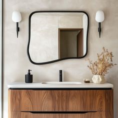 a bathroom vanity with a large mirror above it and a vase on the counter next to it