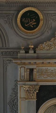 an ornate gold and white fireplace with arabic writing on the wall above it's mantle