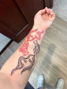 a woman's arm with a red and black tattoo design on the left wrist