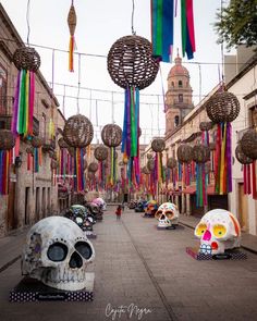 there are many colorful decorations hanging from the ceiling in this city street with skulls on it