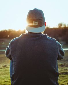 a person wearing a hat sitting on top of a grass covered field