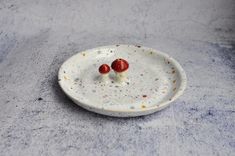 two small red and white toothpicks sitting on top of a white plate with sprinkles