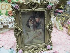 an ornate frame with a painting of two people kissing in front of some other items