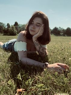 a woman laying in the grass with her hand on her face