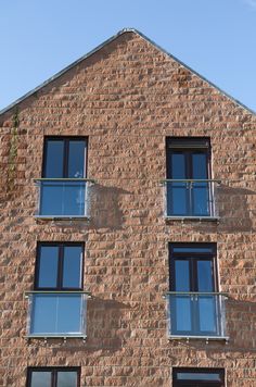 two windows on the side of a brick building with blue sky in the back ground