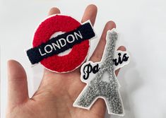 someone is holding two patches that say london, paris and the eiffel tower