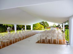 rows of white chairs are set up for an outdoor ceremony