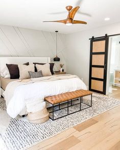 a bedroom with a bed, dresser and ceiling fan in the corner next to it