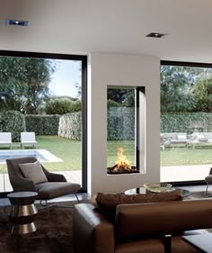 a modern living room with large windows and a fire place in the middle of it