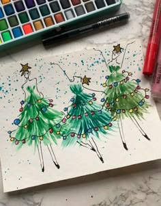 a drawing of two women dressed in green dresses with christmas lights on them, surrounded by markers and crayons