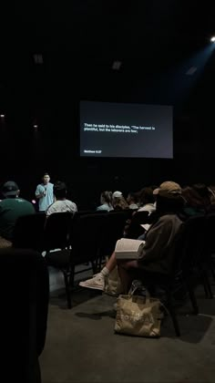 people sitting in chairs watching a presentation on a screen