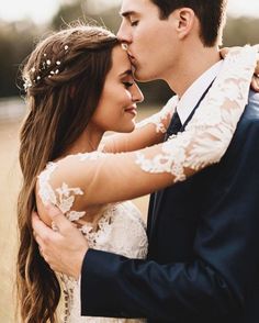 a bride and groom embracing each other in an open field