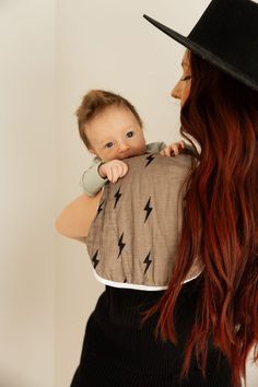 a woman holding a baby wearing a black hat