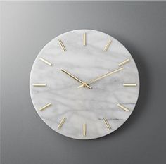 a white marble clock with gold hands on a gray wall