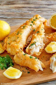 fish and lemons on a cutting board with parsley sprinkled around them