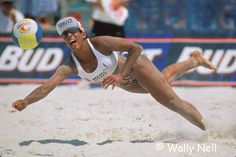 a woman dives to catch a ball on the beach